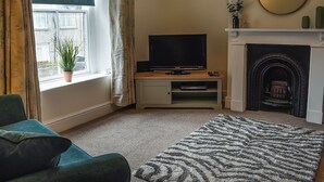 A living room with a television, fireplace, and a view of the outside through a window. - 3 bedroom accommodation in Bala (Bala)