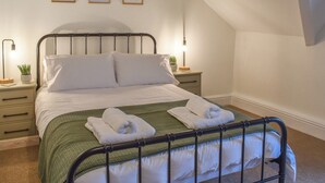 A neatly made bed with white linens and a green bedspread, two bedside lamps, and three framed pictures on the wall. - 3 bedroom accommodation in Bala (Bala)