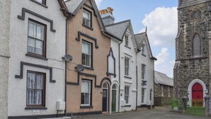 A row of traditional buildings with distinct architectural styles, including a church with a red door and a stone facade. - 3 bedroom accommodation in Bala (Bala)