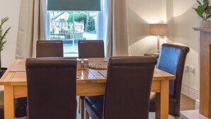 A dining area with a table and four chairs, a window with curtains, a lamp, and a potted plant. - 3 bedroom accommodation in Bala (Bala)