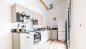 A modern kitchen with white cabinets, a black countertop, and a wooden floor.