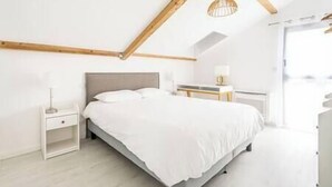 A bedroom with a bed, bedside tables, a lamp, and a window.