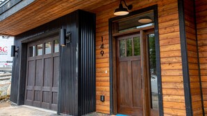 Un edificio de madera con un amplio portón de garaje y una puerta principal.