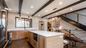 Una cocina moderna con armarios de madera, una isla grande y una zona de comedor con un banco.