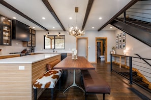 A modern kitchen with a central island, wooden bench seating, and a staircase.