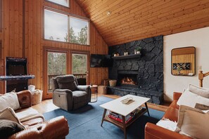 A cozy living room with a stone fireplace, leather furniture, and a flat-screen TV. - Stargazer|A-Frame, Firepit, Spa, Dogs Ok, By Lake! (Big Bear)
