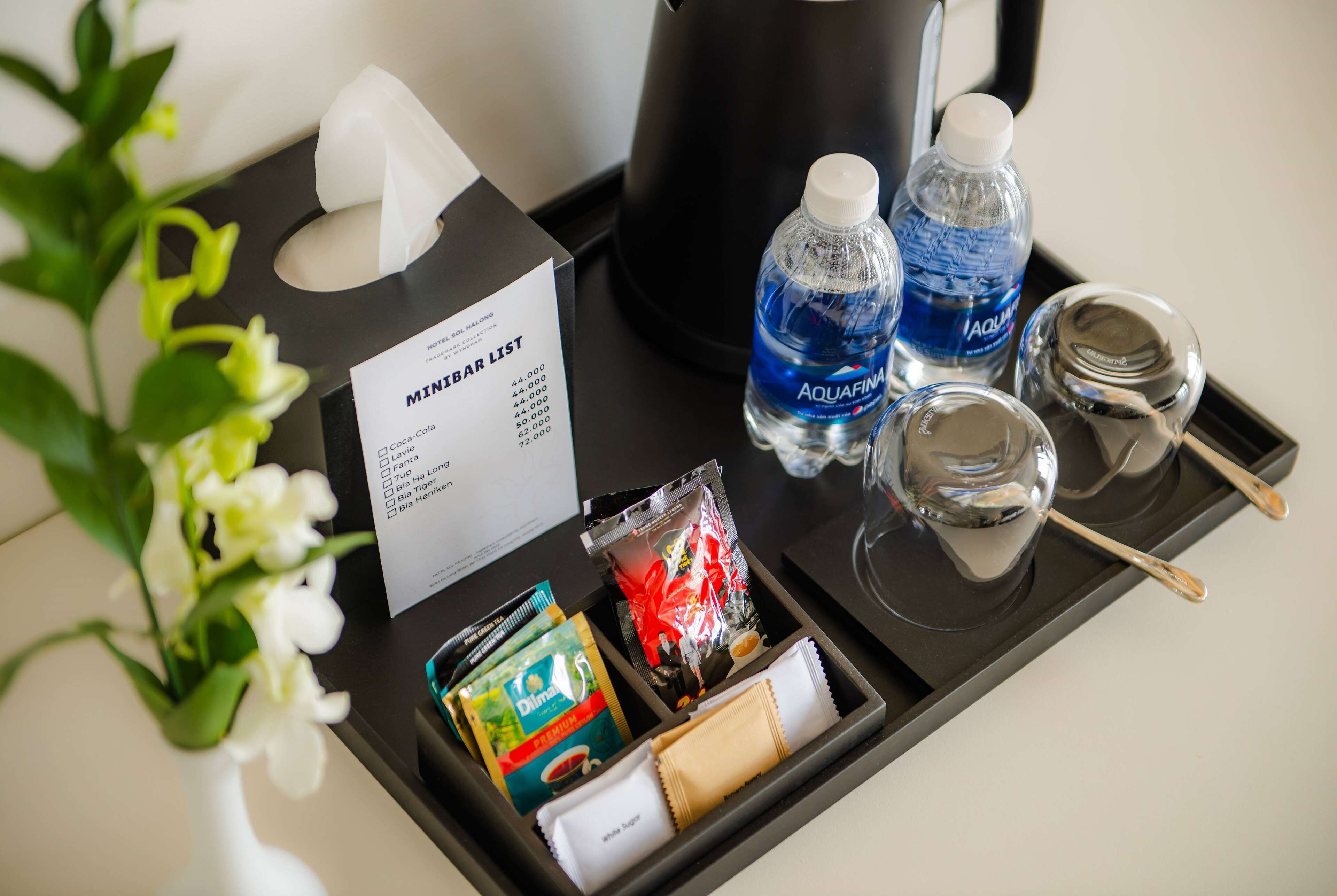 Un plateau de minibar comprenant un menu, des bouteilles d’eau, des en-cas et un verre.
