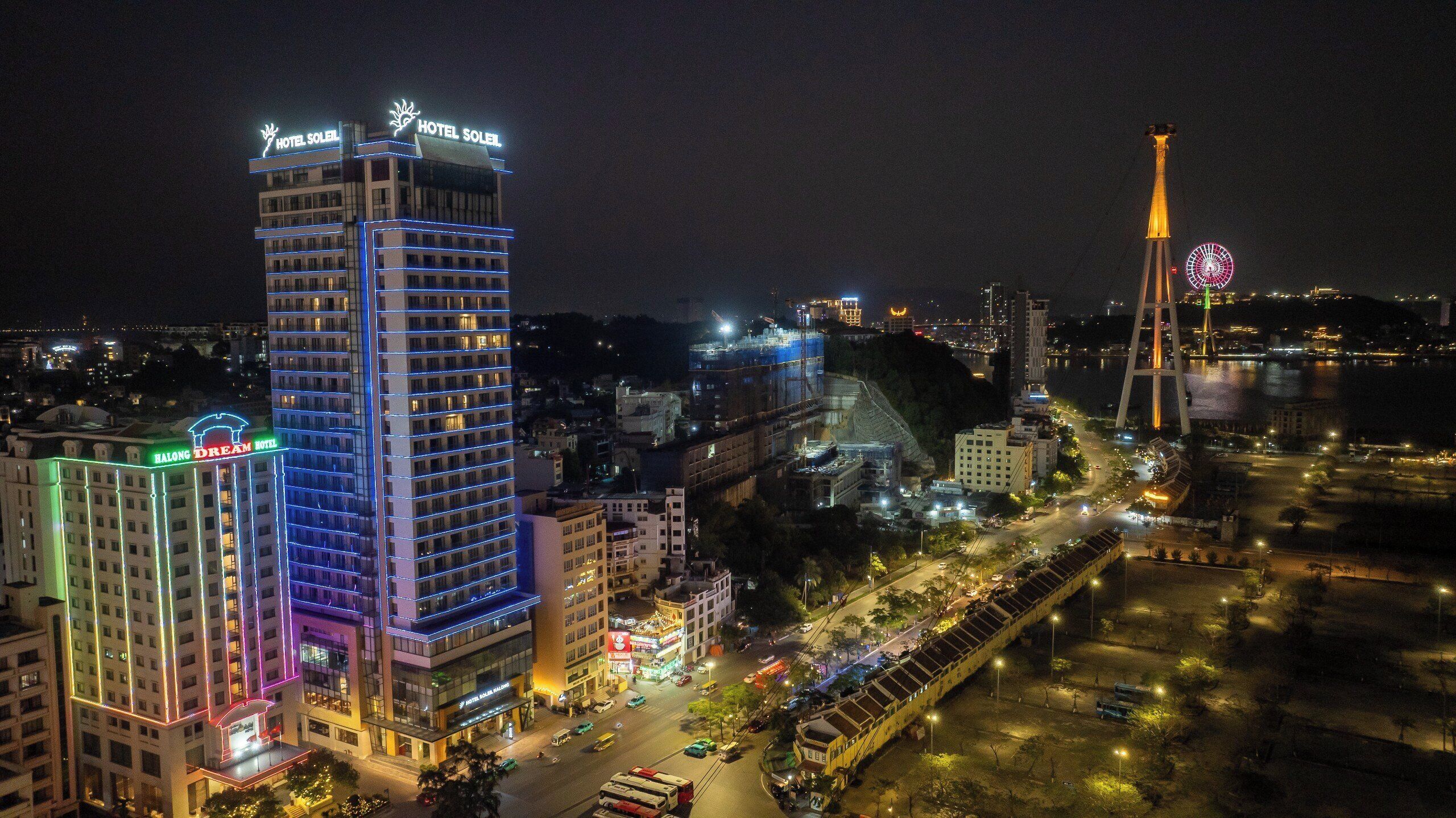 A high-rise hotel with illuminated signage, a prominent tower, and a busy street with vehicles.