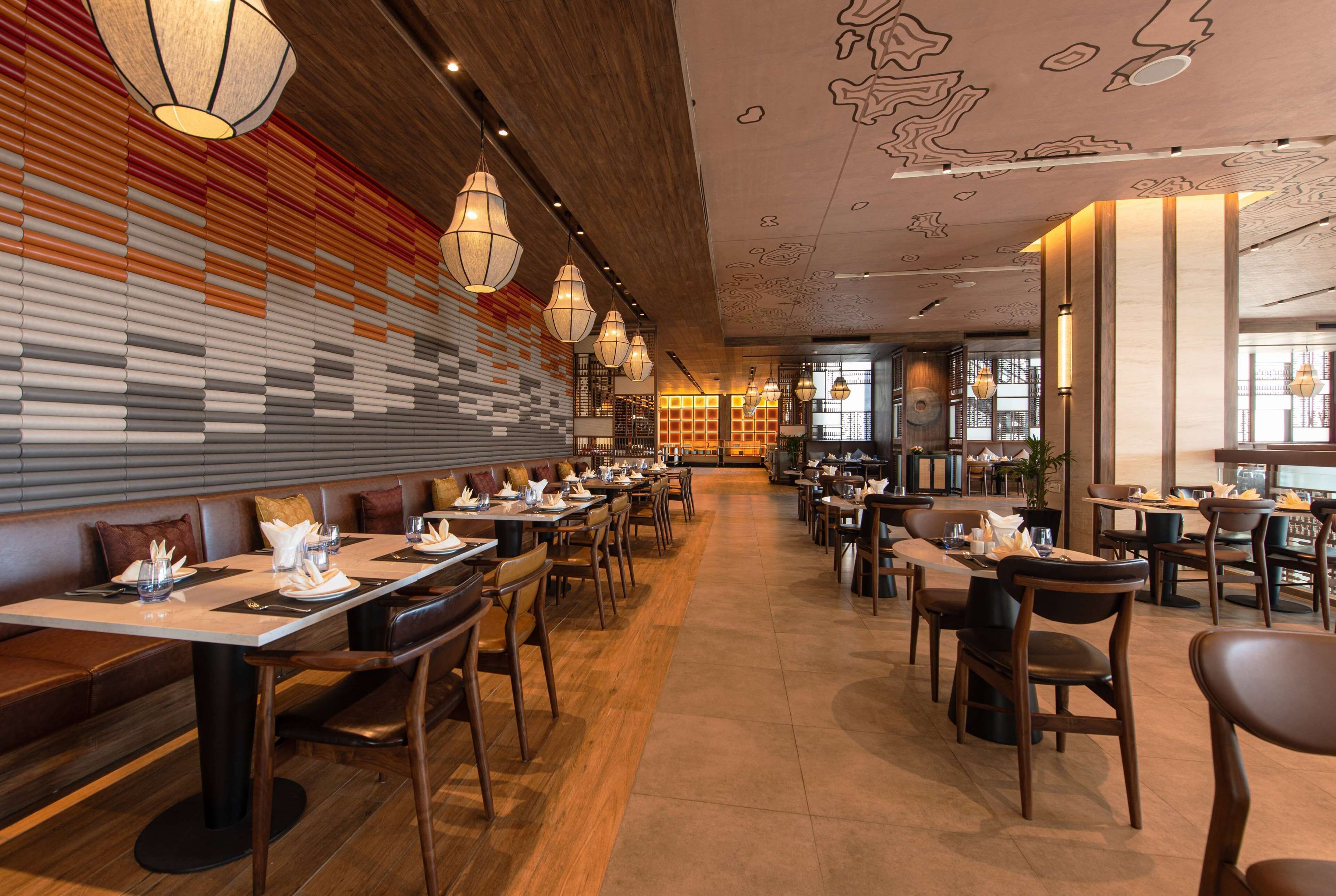 A restaurant with long tables, booths, and hanging light fixtures.