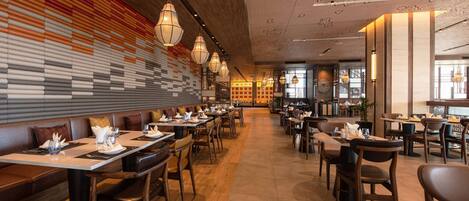 A restaurant with long tables, booths, and hanging light fixtures.
