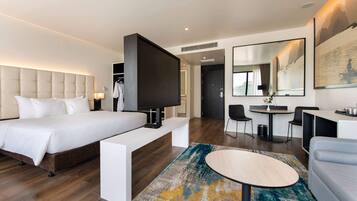 Una habitación de hotel moderna con una cama grande, un escritorio, una zona de estar y una mesa de comedor.