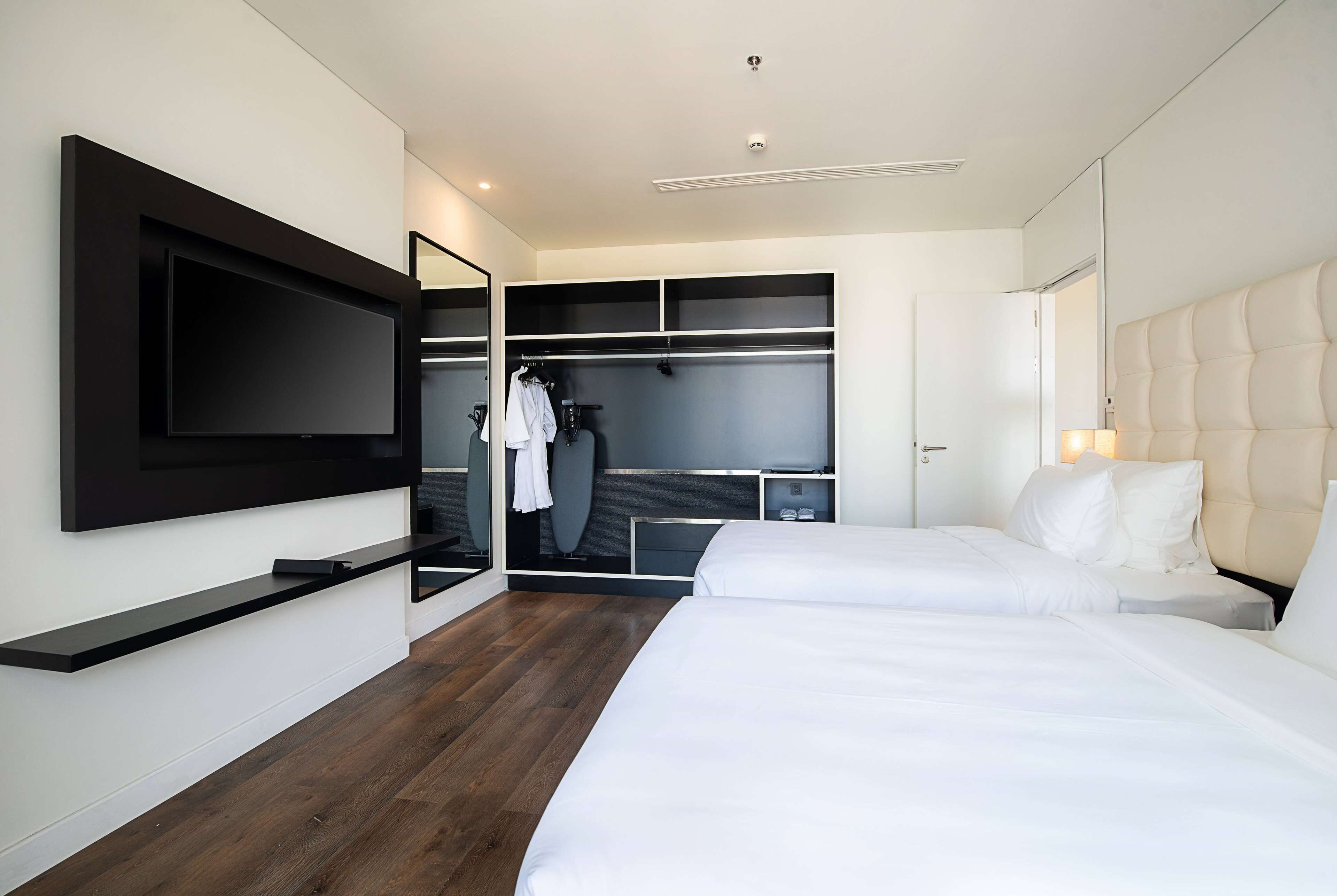Ett modernt hotellrum med en stor säng, en TV som är monterad på väggen, en rymlig klädkammare och en spegel.