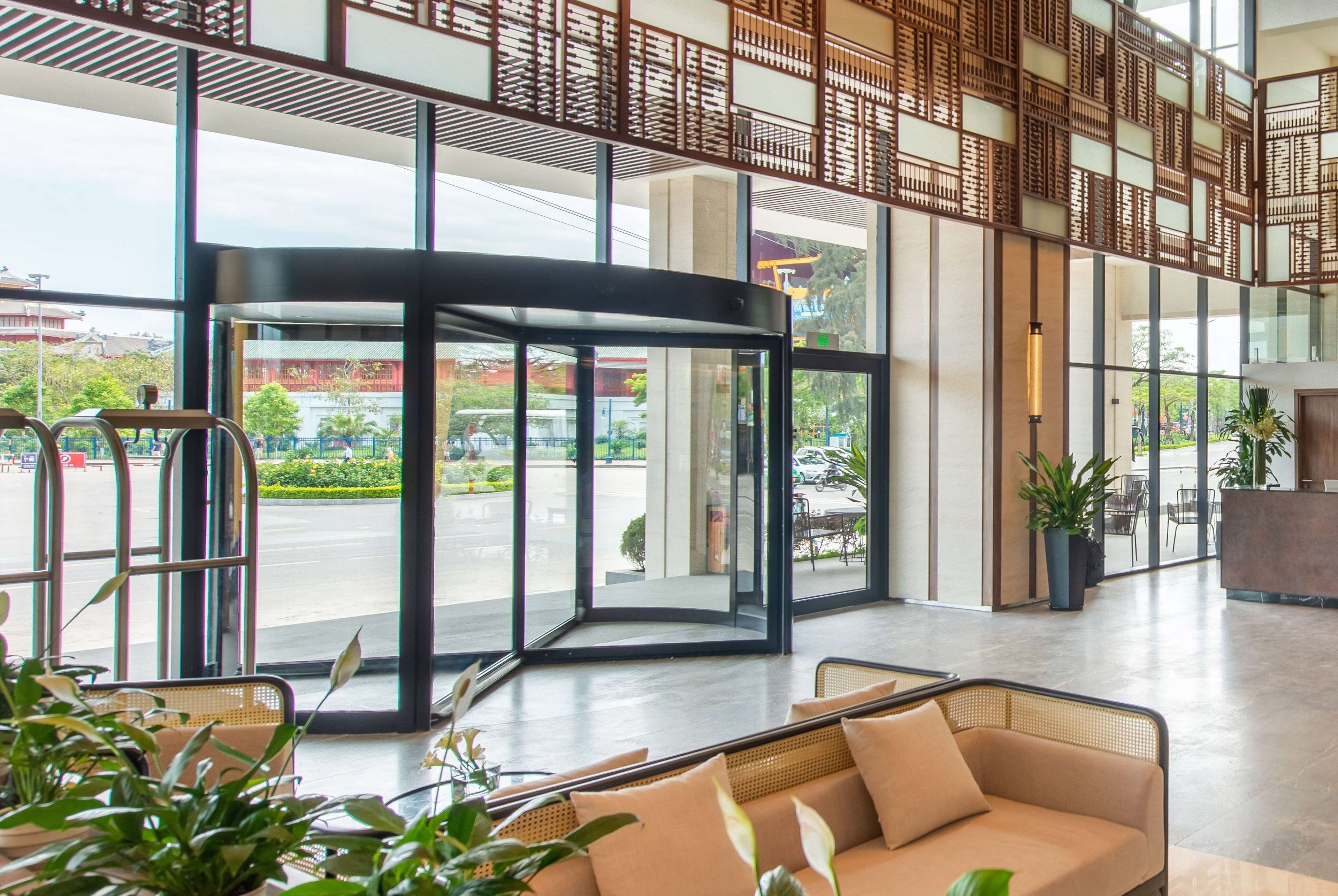 A spacious lobby with a revolving door, comfortable seating, and large windows offering a view of the outdoors.
