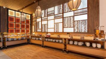 Uma área de buffet com várias estações de serviço, piso de madeira e portas deslizantes em estilo tradicional japonês.
