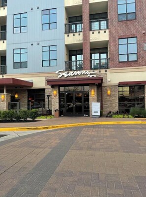 A multi-story building with a 'Seasons' sign above the entrance. - Luxury 2 bedroom unit with pool (Houston)