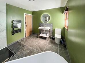 Een badkamer met een badkuip, toilet, wastafel en handdoekhouder.