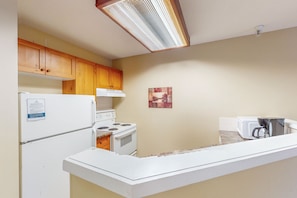A kitchen with wooden cabinets, a white refrigerator, a stove, and a microwave. - Marketplace Lodge - Whistler Premier (Whistler)