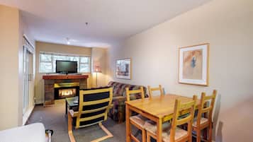 A cozy living room with a fireplace, a television, and a dining area with wooden furniture.