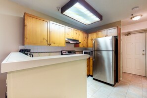 Una cocina con armarios de madera, un refrigerador de acero inoxidable, un microondas y un horno empotrado.