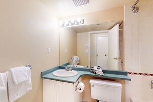 Un baño con lavamanos, espejo, inodoro y toallero.