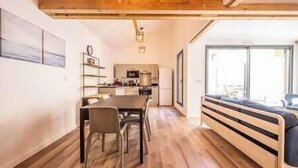 A modern kitchen with wooden cabinets, a dining table with chairs, and a built-in bench with cushions. - Apartment Comfortable in the centre of Pau: parking, AC... (Pau)