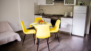 A modern kitchen with white cabinets, a dining table with yellow chairs, and a refrigerator.
