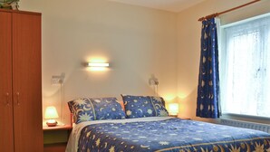 A bedroom with a bed, nightstands, a wardrobe, and a window with curtains. - 3 bedroom accommodation in Llanfair Caereinion, near Welshpool (Llanfair Caereinion, near Welshpool)