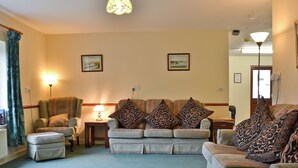 A living room with a sofa set, a side table with a lamp, and two framed pictures on the wall. - 3 bedroom accommodation in Llanfair Caereinion, near Welshpool (Llanfair Caereinion, near Welshpool)