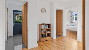 Un hall d’entrée spacieux, doté d’un plancher en bois, d’une bibliothèque et offrant une vue sur une chambre à coucher avec un lit et une fenêtre.