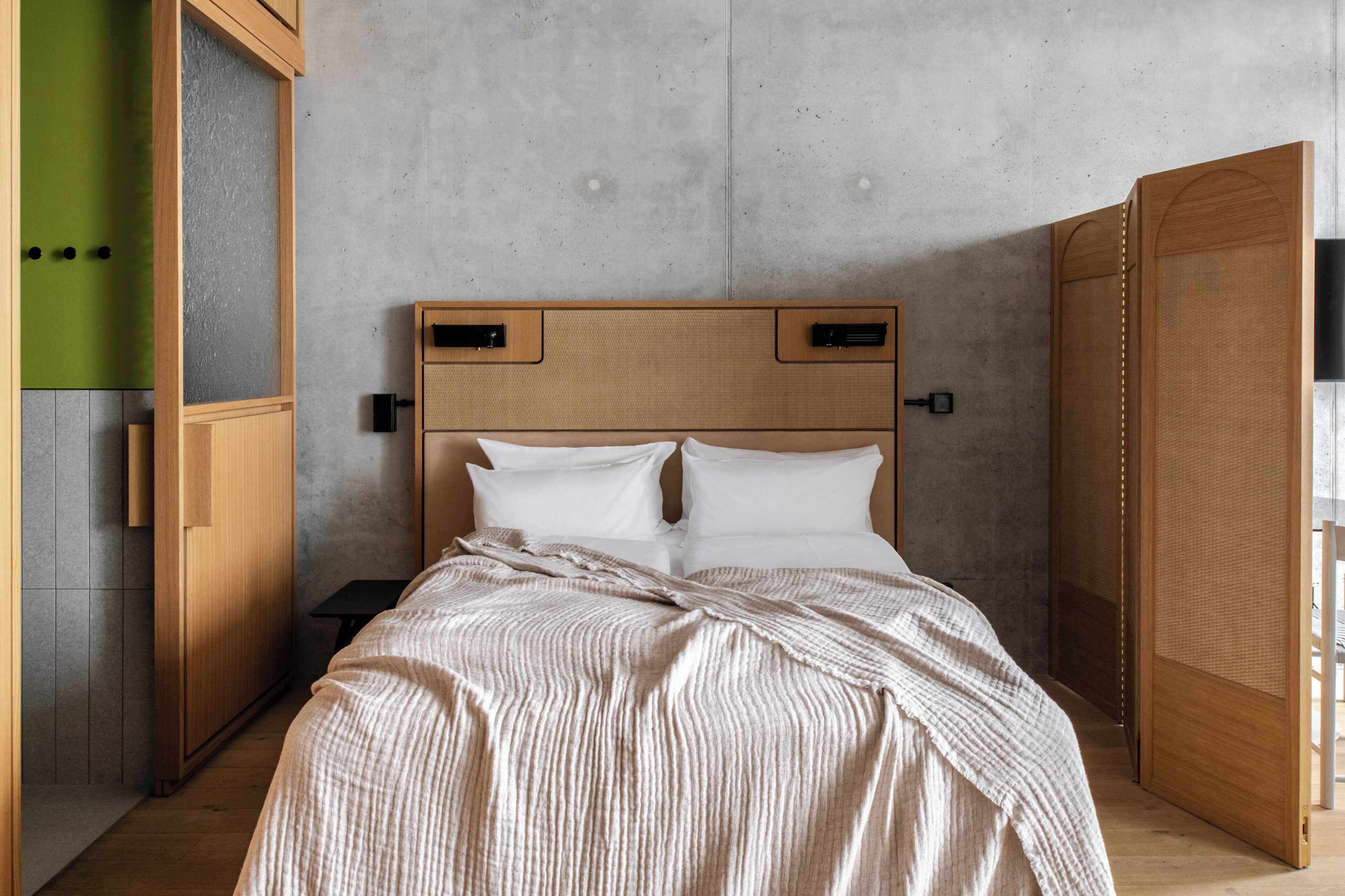 A bedroom with a bed, wooden headboard, and a green wall.