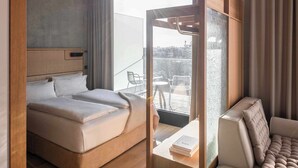 Habitación de hotel moderna con una cama grande, un rincón de descanso y vistas a la ciudad.