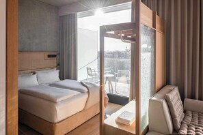 Ein modernes Hotelzimmer mit einem großen Bett, einer Sitzecke und Blick auf die Stadt.