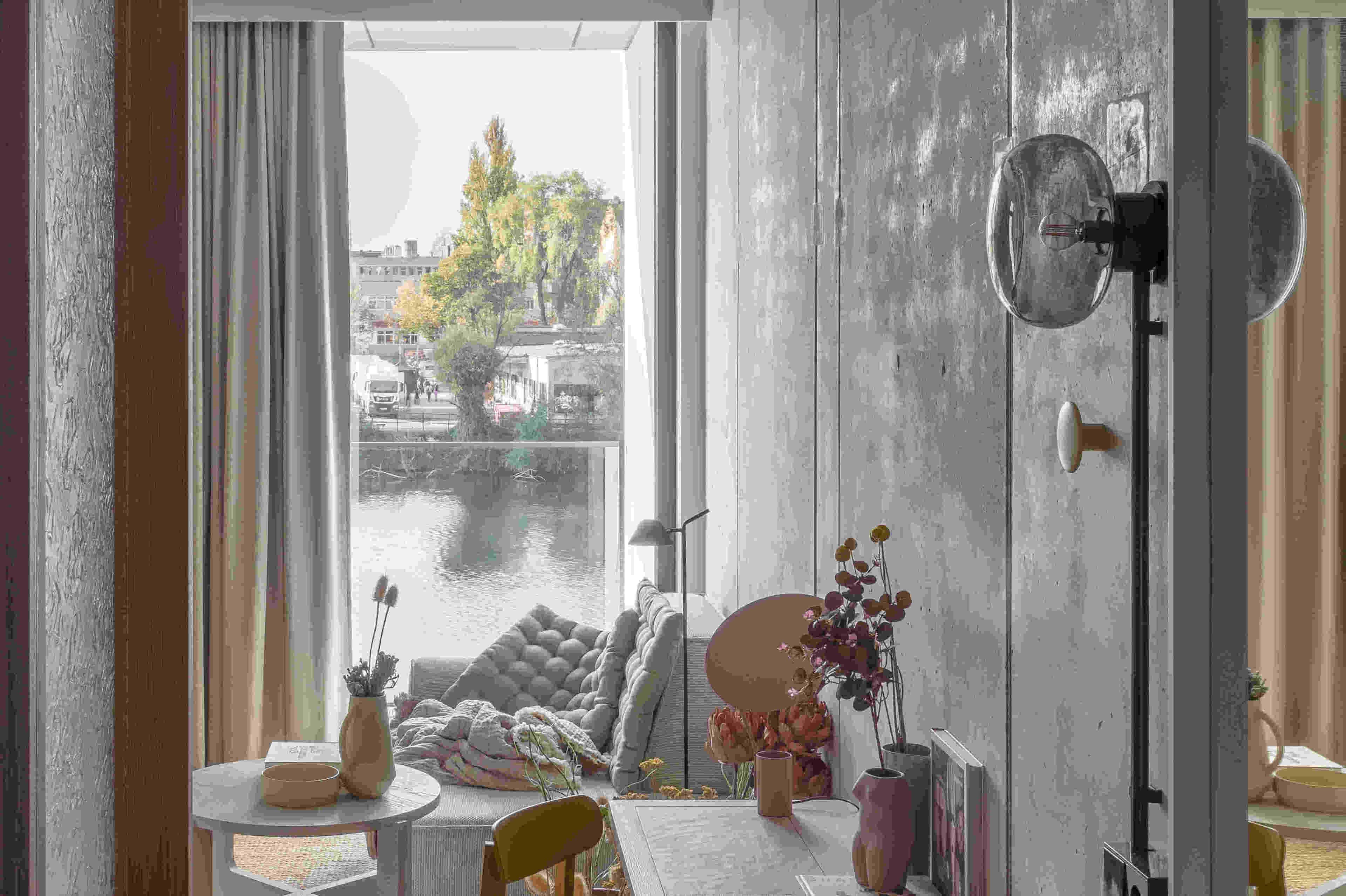 Una habitación con un ventanal grande, un espejo redondo, una mesita y una silla.