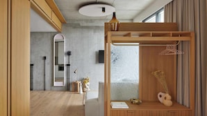 Un dormitorio moderno con una cama de madera, una mesita de noche con un florero y un armario con perchero.