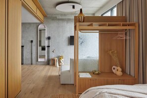 Ein modernes Schlafzimmer mit einem Holzbett, einem Nachttisch mit einer Vase und einem Kleiderschrank mit Kleiderstange.