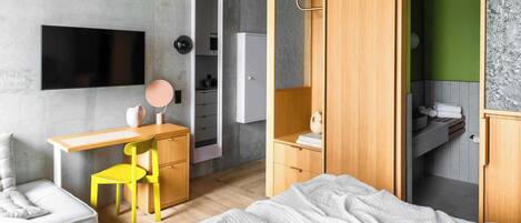 A modern bedroom with a bed, a desk, a chair, a TV, and a wardrobe.