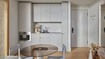 A modern kitchen with white cabinets, a glass table, and a vase with flowers.