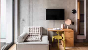 A modern room with a sofa, a desk, a chair, a television, and a door.