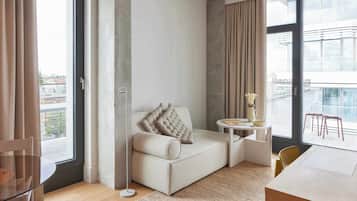 Una sala de estar moderna con un sofá, una mesita y vistas a la ciudad a través de amplios ventanales.