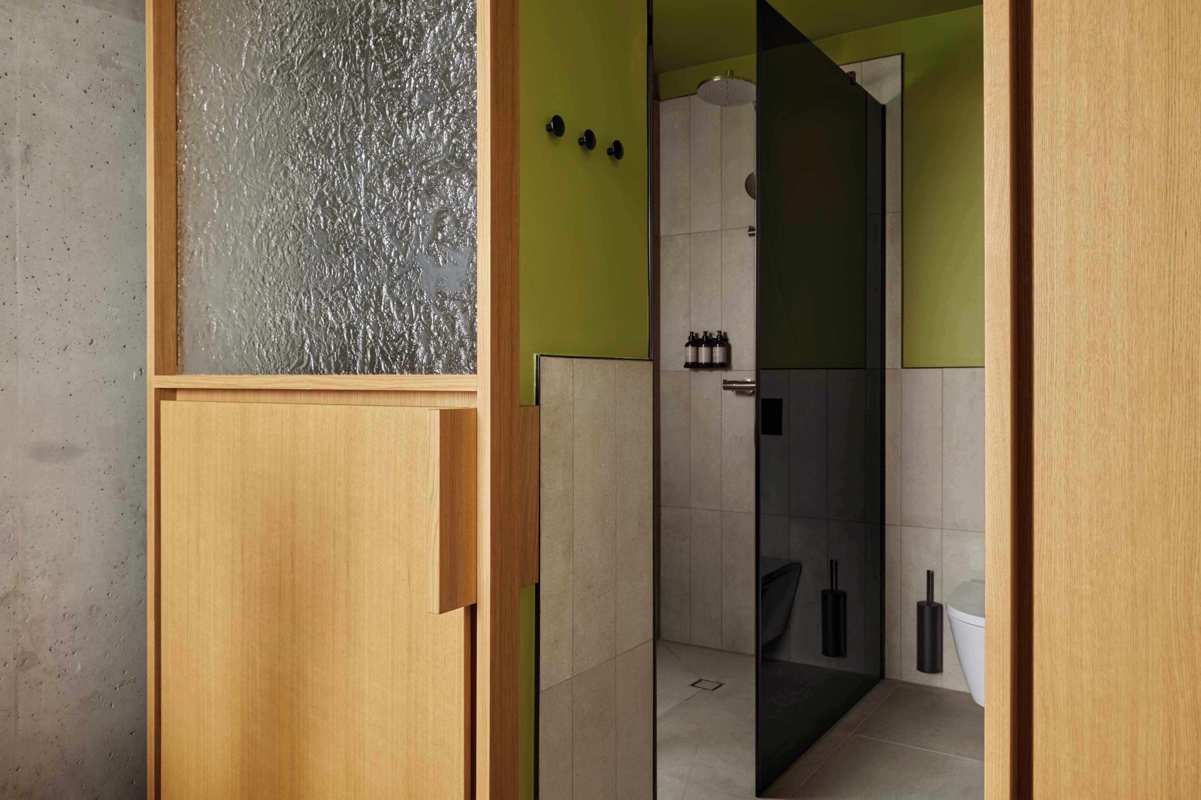 A bathroom with a shower, toilet, and a glass partition.