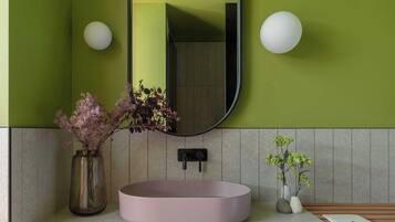 A bathroom with a round pink sink, a mirror, and two wall-mounted lights.