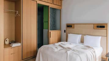 Un dormitorio con cama, un armario de madera y un baño visible a través de una puerta de cristal.