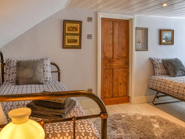 A bedroom with two beds, a wooden door, and framed pictures on the wall.