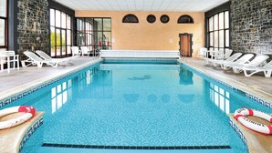 Piscina interna com paredes revestidas de azulejos, espreguiçadeiras e boias.