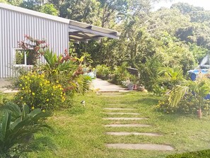 Um jardim com um caminho que leva a um edifício com fachada de metal corrugado.