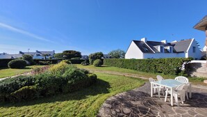 A residential area with a well-maintained lawn, stone pathway, and a patio with outdoor furniture.