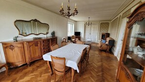 A dining room with a wooden herringbone floor, a large mirror, a chandelier, and a television in the background.