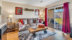 A living room with a sofa, coffee table, and a sliding glass door leading to an outdoor area. - Freshly Remodeled Condo - Fall Creek Resort (Branson)