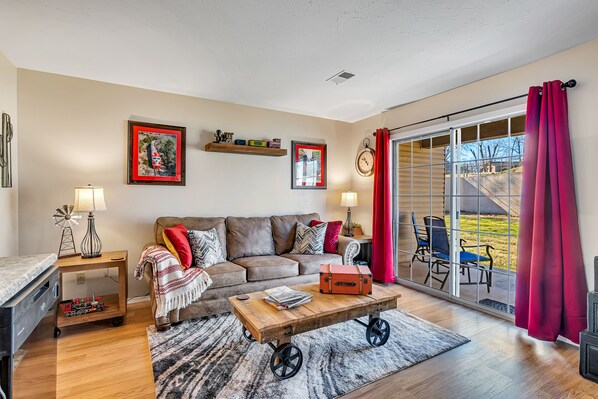A living room with a sofa, coffee table, and a sliding glass door leading to an outdoor area.