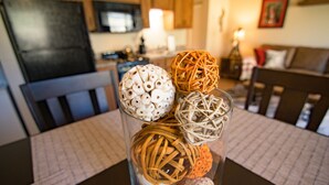 A dining table with a glass centerpiece containing decorative items. - Freshly Remodeled Condo - Fall Creek Resort (Branson)